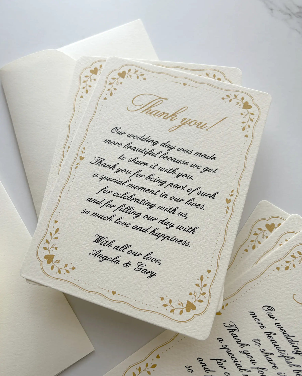 Stack of custom thank you cards with a gold heart frame and script message on textured cream paper