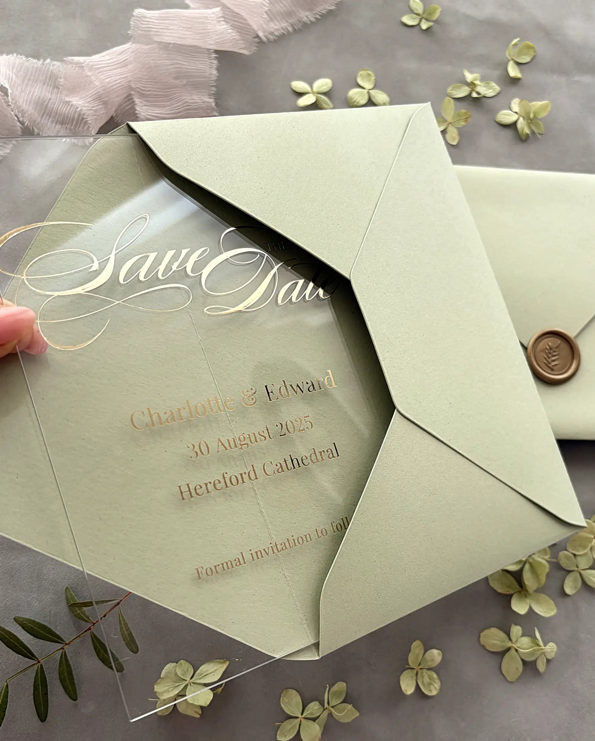 Acrylic Save the Date card with gold foil script and wedding details, slipped into sage green envelope with gold wax seal — Polina Perri