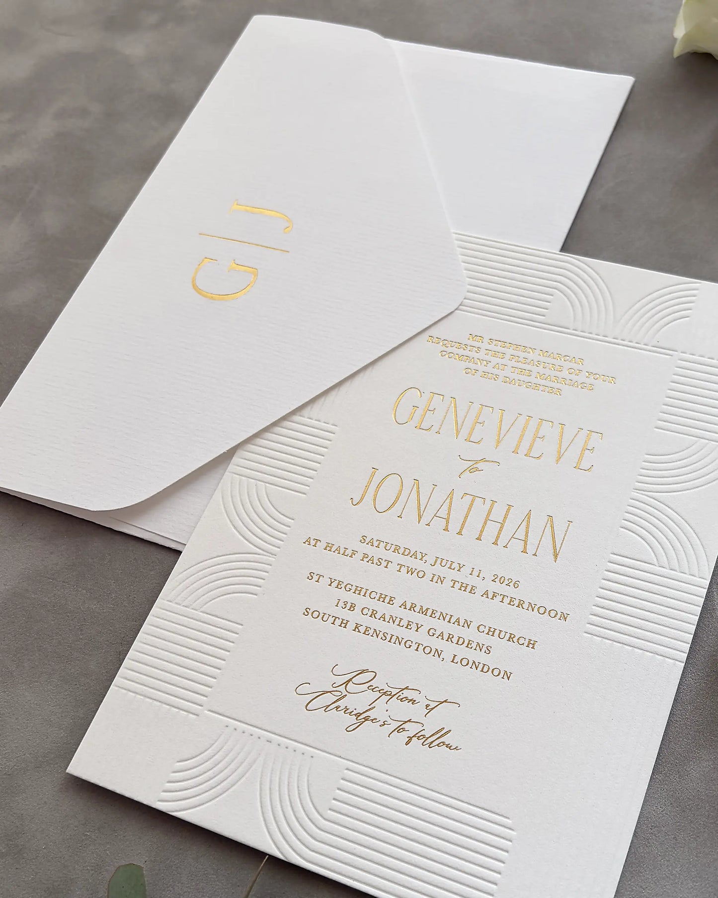 Art Deco invitation card with embossed concentric wave borders and gold foil couple's names, matching envelope with personalized monogram on gray surface — Polina Perri