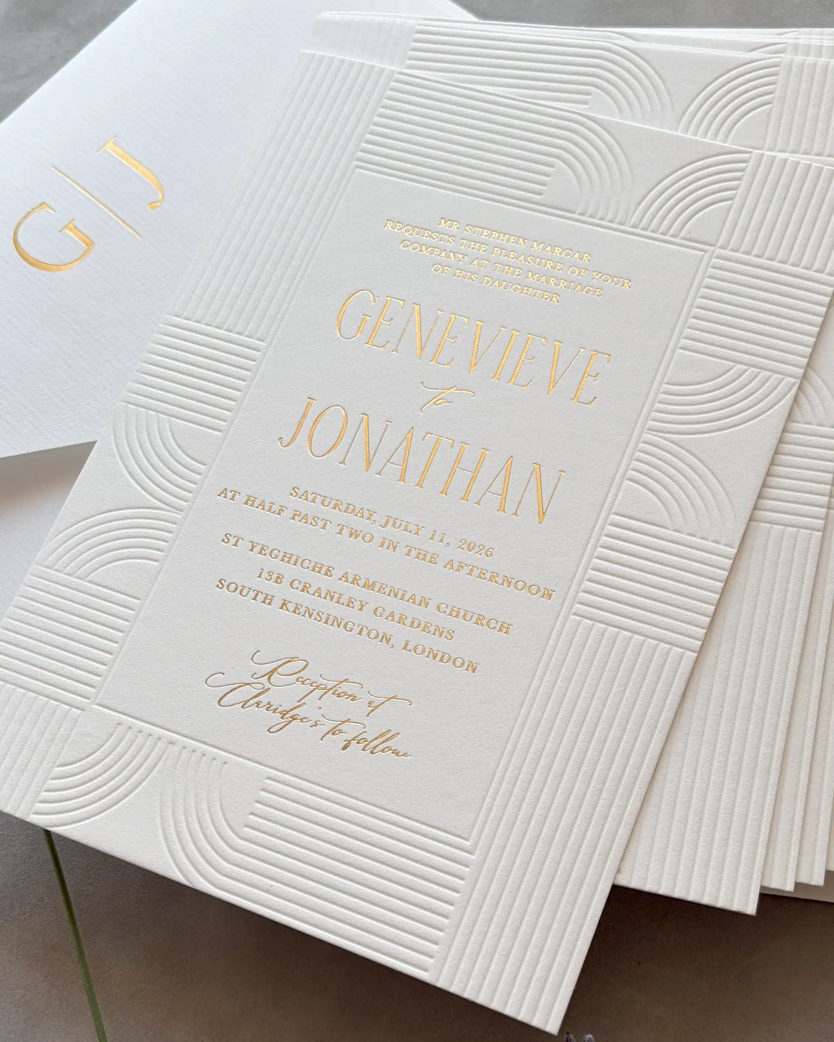 Art Deco wedding invitation bundle with embossed wave-pattern cards and gold foil text, white envelope with personalized monogram visible, stacked arrangement on neutral surface — Polina Perri