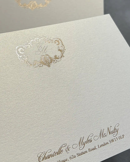 Close-up of shimmer cardstock thank-you card with gold foil crest monogram and foil-pressed names on the lower edge