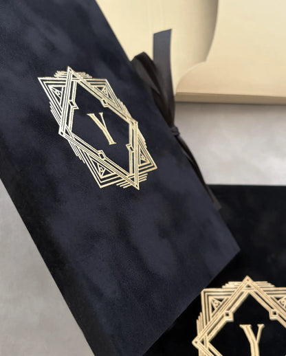 Great Gatsby Folio Invitation close-up of gold foil Art Deco monogram on black velvet cover with black ribbon tie — Polina Perri