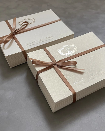 Bundles of personalised thank-you cards with gold foil monogram and the couple's names, tied with ribbon