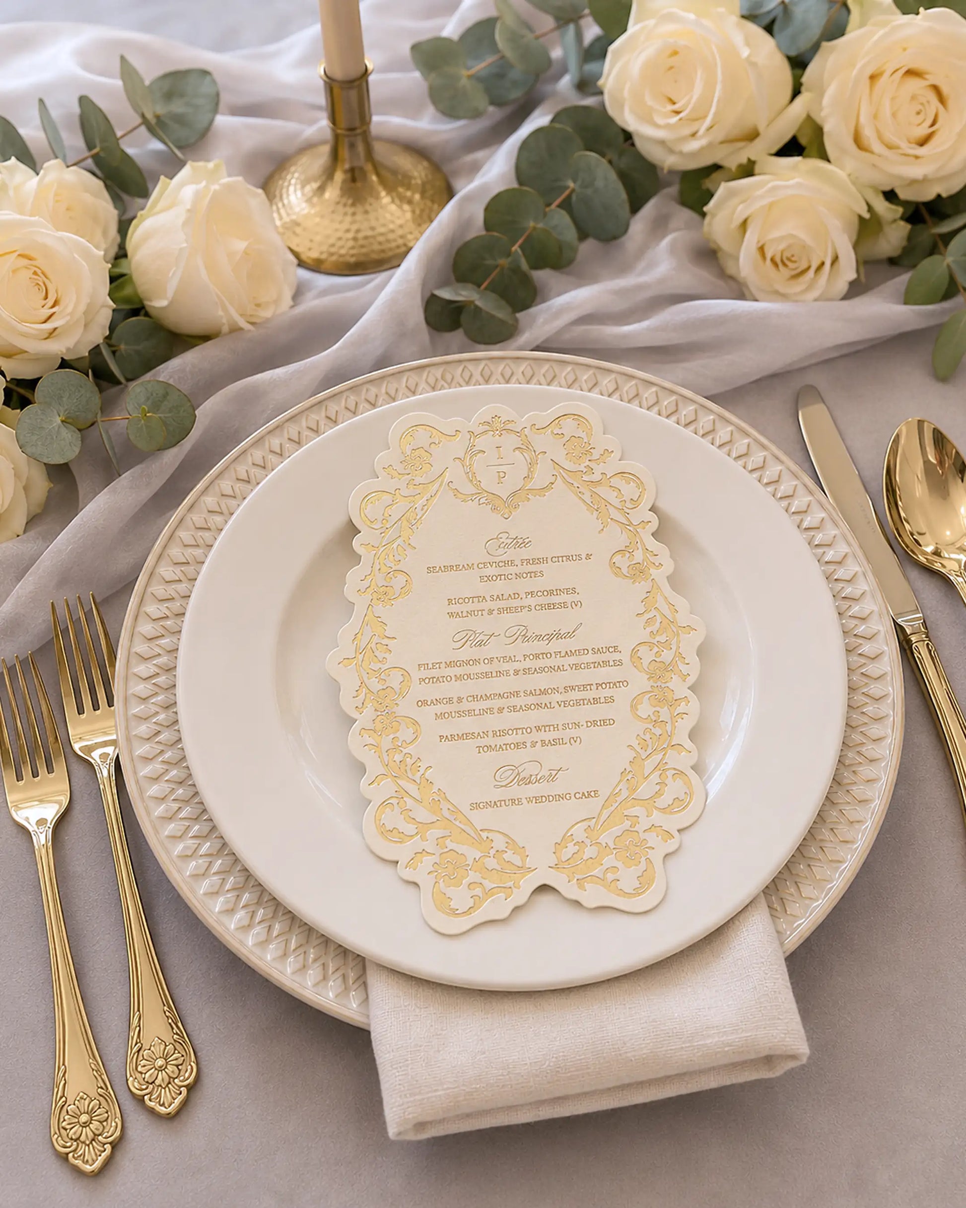 Belle wedding menu with gold foil-pressed floral border, placed on a charger plate at a table setting with gold flatware and cream roses | Polina Perri