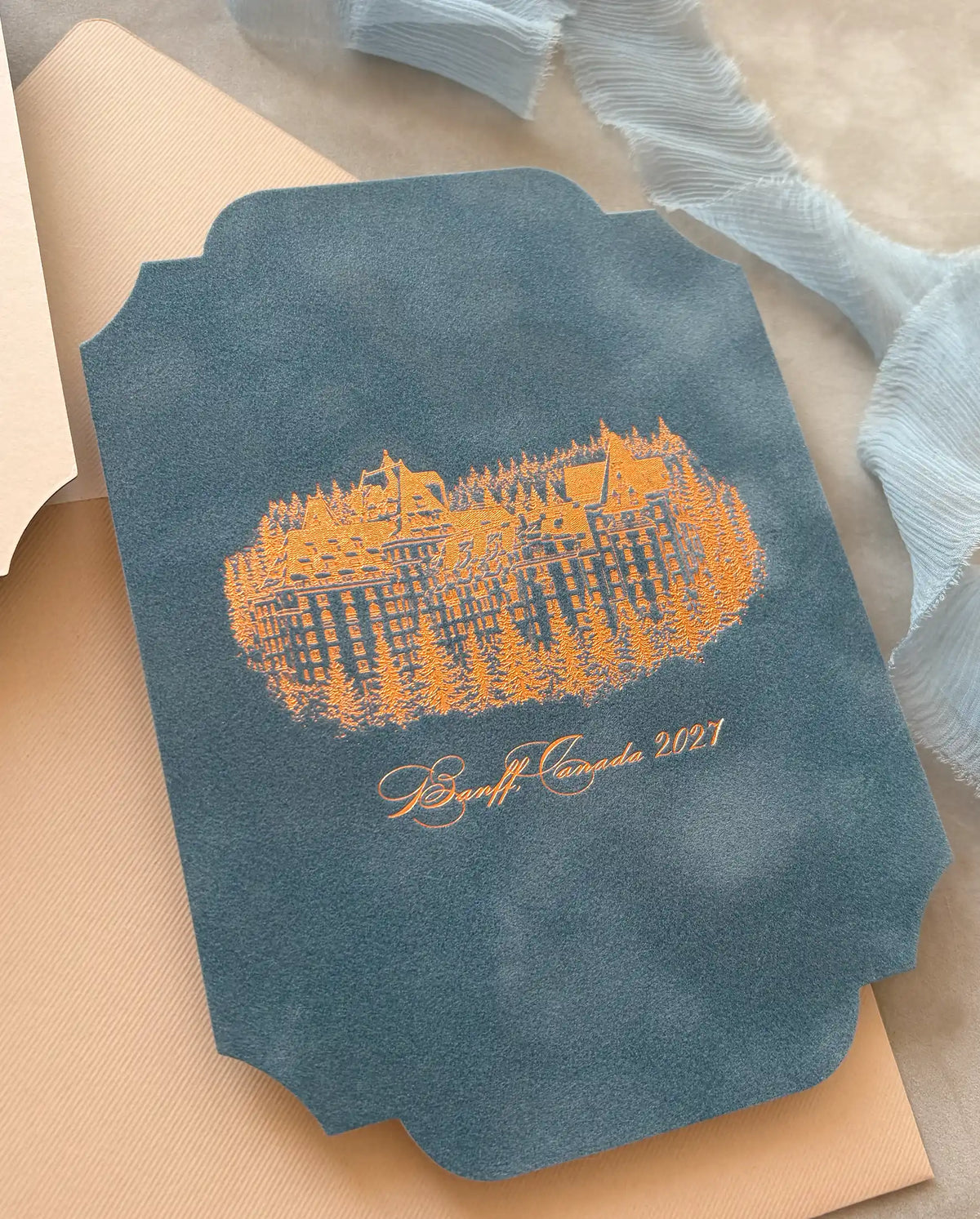 Venue Velvet Save the Date dusty blue velvet side with copper foil illustration of Fairmont Banff Springs on cream envelope — Polina Perri